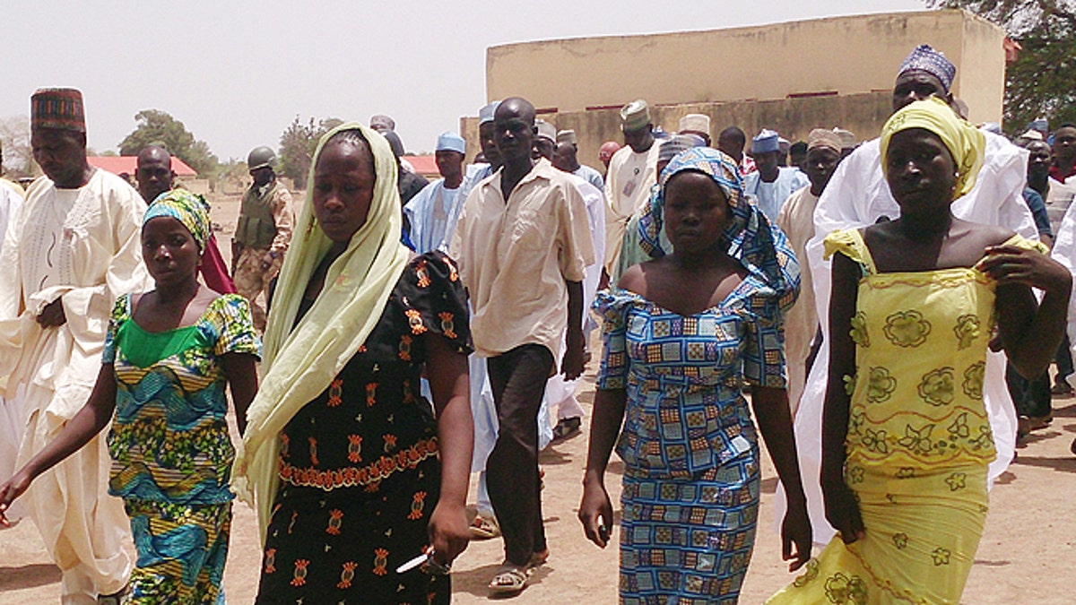 FILE - In this Monday April 21, 2014 file photo, four female students of the government secondary school Chibok, who were abducted by gunmen and reunited with their families, walk in Chibok, Nigeria. A civil society group says Wednesday April 30, 2014, that villagers are reporting that scores of girls and young women who were recently kidnapped from a school in Nigeria are being forced to marry Islamic extremists. A federal senator for the area in northeast Nigeria wants the government to get international help to rescue the more than 200 missing girls kidnapped by Boko Haram from a school two weeks ago. (AP Photo/ Haruna Umar, File)