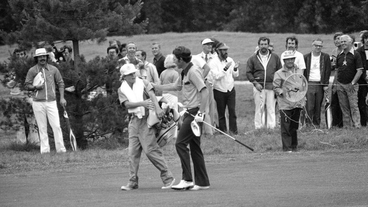 FILE - In this June 16, 1974, file photo, Peter McGarey, 16, of Scottsdale, Ariz., reaches to offer congratulations to Hale Irwin after the latter's fairway shot on the 18th reached the green and prior to Irwin's winning the U.S. Open golf championship in Mamaroneck, N.Y. Irwin closed with a 73 to capture the first of his three U.S. Open. Irwin won at 7-over 287. There has not been a higher winning score in relation to par at any major since then. (AP Photo/File)