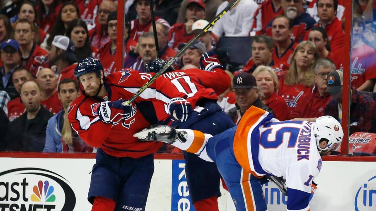 Washington Capitals center Brooks Laich (21), right wing Troy Brouwer (20) and New York Islanders right wing Cal Clutterbuck (15) collide during the first period of Game 5 in the first round of the NHL hockey Stanley Cup playoffs, Thursday, April 23, 2015, in Washington. (AP Photo/Alex Brandon)