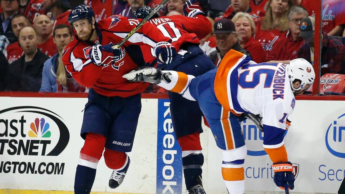 Washington Capitals center Brooks Laich (21), right wing Troy Brouwer (20) and New York Islanders right wing Cal Clutterbuck (15) collide during the first period of Game 5 in the first round of the NHL hockey Stanley Cup playoffs, Thursday, April 23, 2015, in Washington. (AP Photo/Alex Brandon)