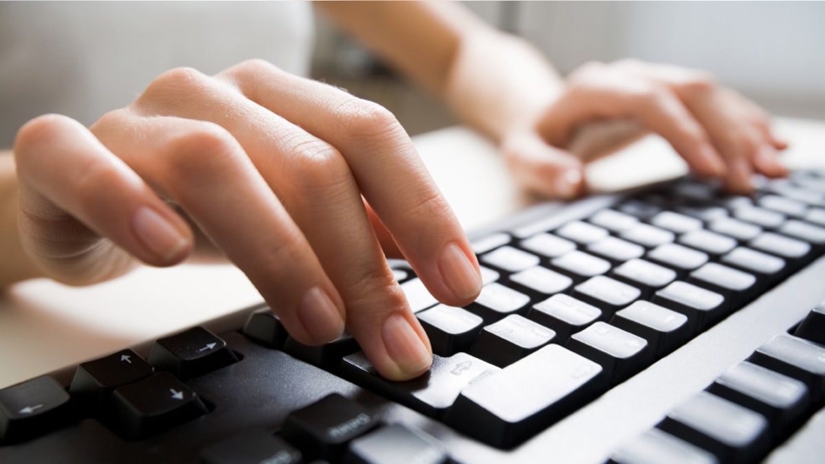 Close-up of female hands touching buttons of black computer keyboard