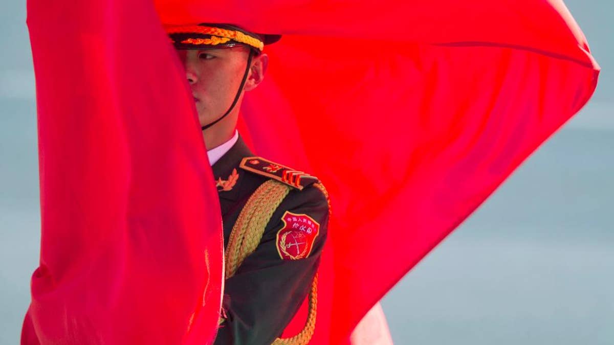 A member of a Chinese honor guard holds a flag before a welcome ceremony for German Chancellor Angela Merkel held outside the Great Hall of the People in Beijing, China, Thursday, Oct. 29, 2015.(AP Photo/Ng Han Guan)