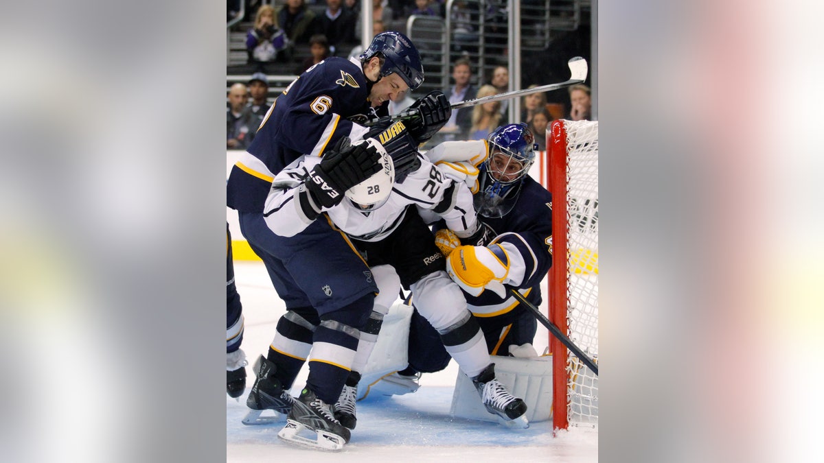 St. Louis Blues defenseman Kent Huskins, left, pushes Los Angeles Kings center Jarret Stoll in front of St. Louis Blues goalie Jaroslav Halak during the second period of an NHL hockey game in Los Angeles, Tuesday, Oct. 18, 2011. (AP Photo/Jae C. Hong)