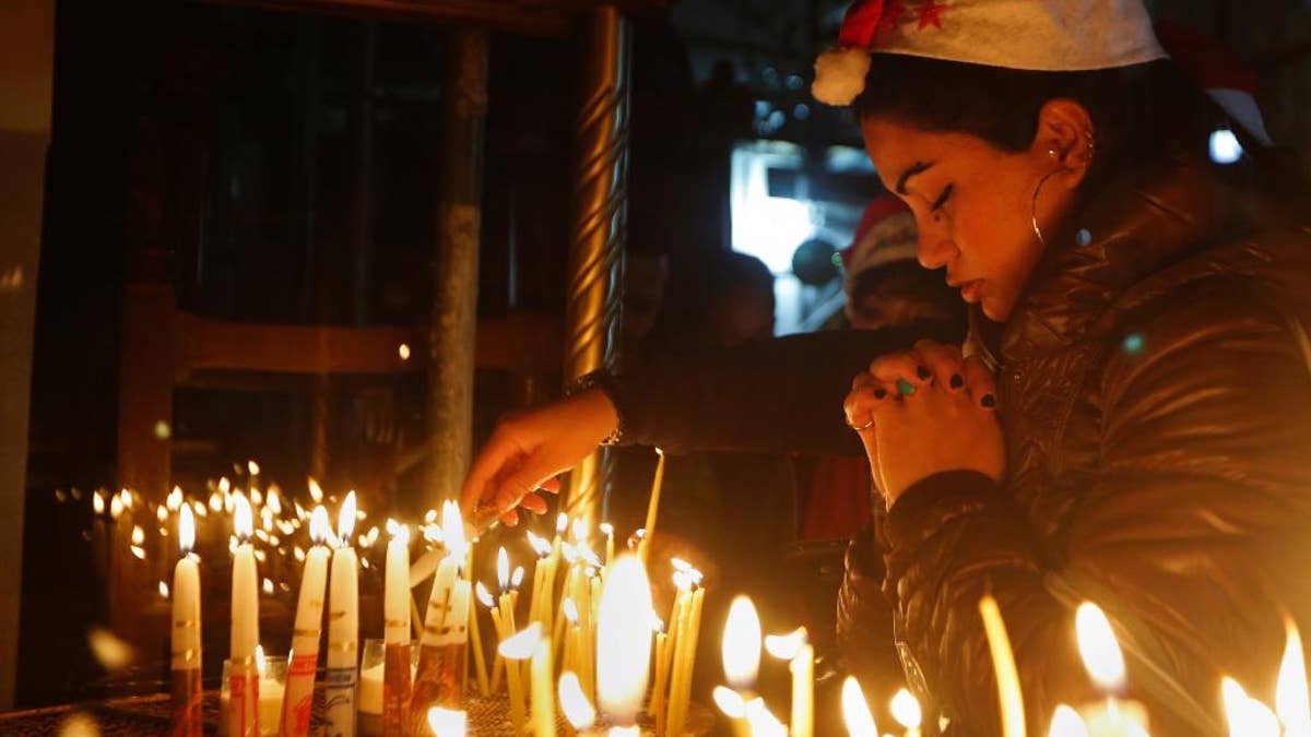 A Christian worshipper prays after lighting a candle on Christmas Eve at the Church of the Nativity, built atop the site where Christians believe Jesus Christ was born, in the West Bank City of Bethlehem, Saturday, Dec. 24, 2016. (AP Photo/Majdi Mohammed)