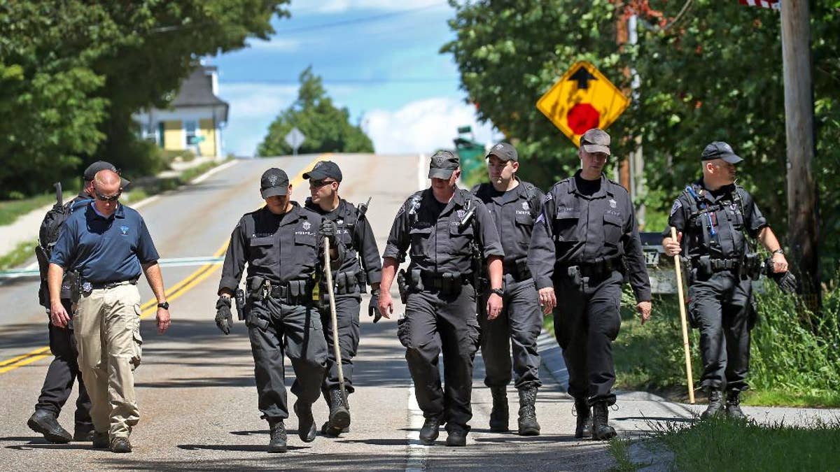 State Police walk down the street after searching through the woods for evidence after a woman visiting her mother was found slain, Tuesday, Aug. 9, 2016 in Princeton, Mass. Police found the body of Vanessa Marcotte on Sunday night about a half-mile from her mother's home, Worcester District Attorney Joseph Early Jr. said. She was visiting from New York City and was reported missing Sunday after she didn't return home. (David L. Ryan/The Boston Globe via AP)
