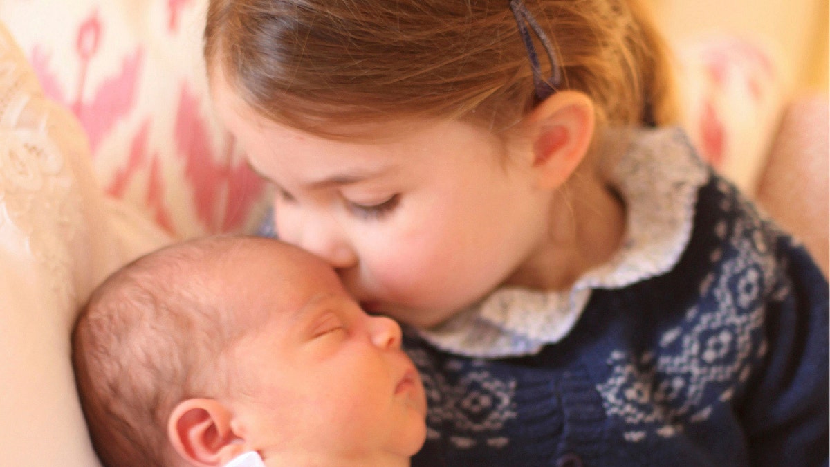 In this May 2, 2018 photograph provided by Kensington Palace, Britain's Princess Charlotte cuddles her brother Prince Louis, on her third birthday, at Kensington Palace, in London. Prince William and his wife Kate have released two pictures documenting the early days of Britainâs newest prince. (Duchess of Cambridge/via AP)
