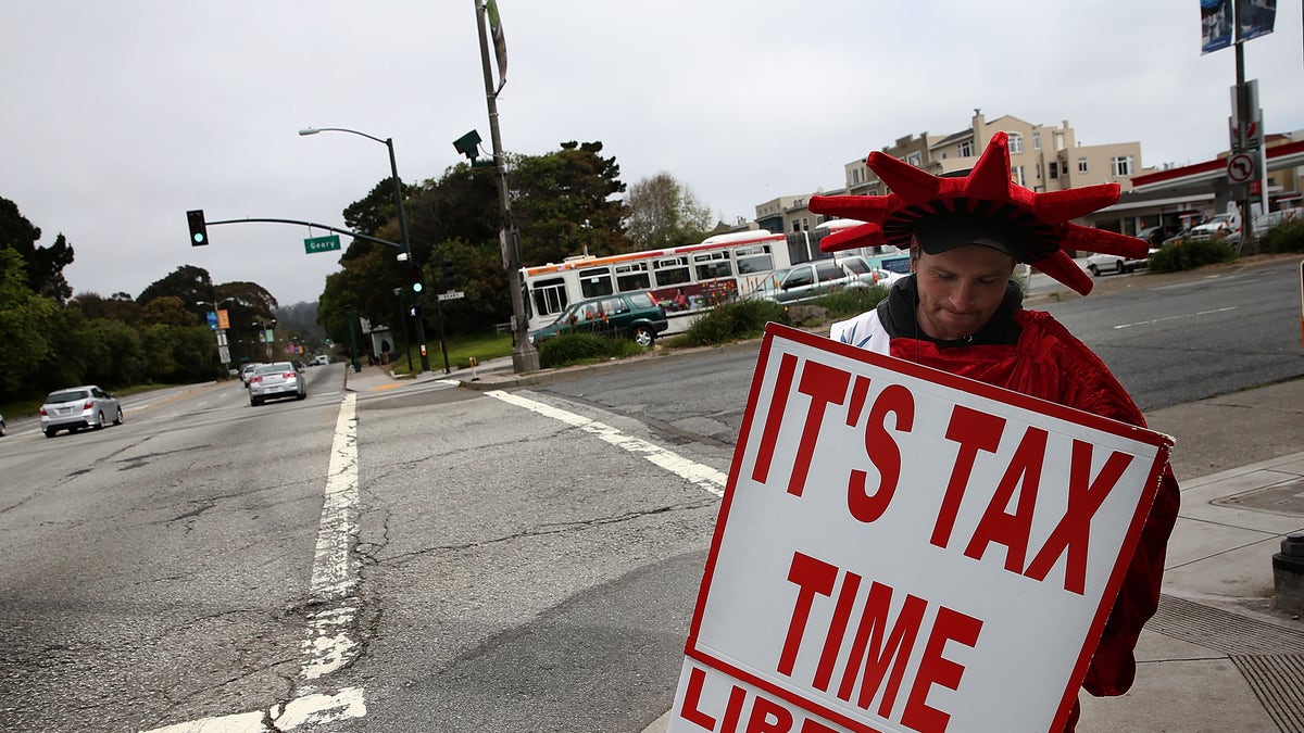Aaron Lee holds a sign advertising income tax services for Liberty Tax Service 
