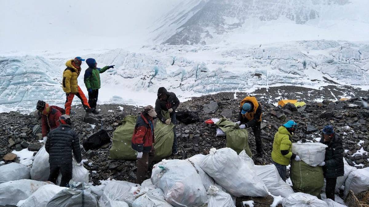 In this Monday, May 8, 2017 photo released by Xinhua News Agency, people collect garbage at the north slope of the Mount Qomolangma in southwest China's Tibet Autonomous Region. Workers and volunteers collected four tons of garbage from the Chinese north side of Mount Everest in the first five days of a cleanup operation, state media reported Thursday, May 11, 2017. (Awang Zhaxi/Xinhua via AP)