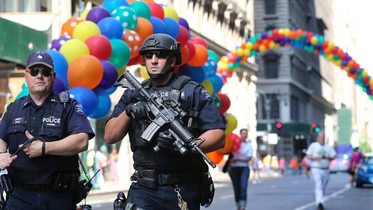 Police officers walk along the street near the parade route of the New York City Pride Parade on Sunday, June 26, 2016, in New York City. A year after New York City's storied gay pride parade celebrated a high point with the legalization of gay marriage nationwide, the atmosphere this year couldn't be more different. Parades in New York and other major cities Sunday will feature increased security, anti-violence messages and tributes to those killed in this month's massacre at a gay nightclub in Florida. (AP Photo/Mel Evans)