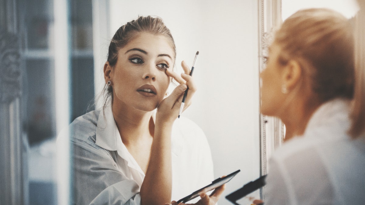 Woman applying makeup iStock