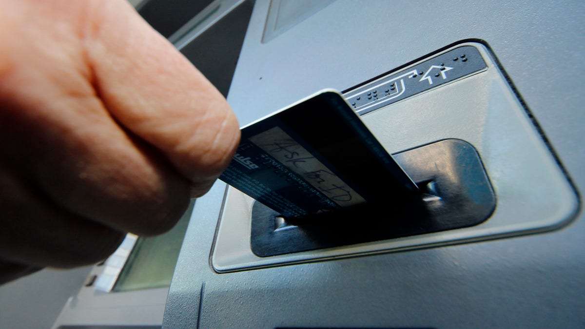 FILE - In this Saturday, Jan. 5, 2013 file photo, a person inserts a debit card into an ATM machine in Pittsburgh. A gang of cyber-criminals stole $45 million in a matter of hours by hacking their way into a database of prepaid debit cards and then draining cash machines around the globe, federal prosecutors said Thursday, May 9, 2013. (AP Photo/Gene J. Puskar, File)