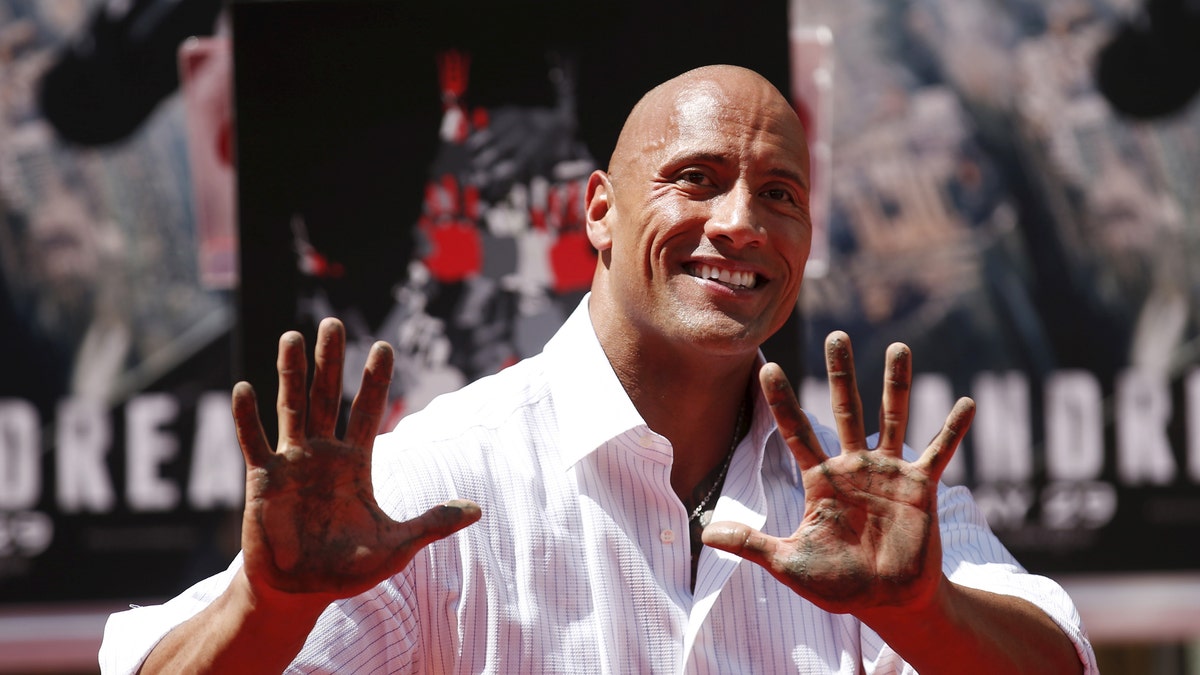 Actor Dwayne "The Rock" Johnson poses after putting his hands in cement during his hand and footprints ceremony in the forecourt of the TCL Chinese Theatre in celebration of his new movie "San Andreas," in Hollywood, California May 19, 2015. REUTERS/Danny Moloshok - RTX1DPC2