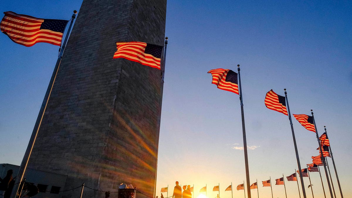 Tourists walk around the base of the Washington Monument on Presidents Day weekend as the sunsets Sunday, Feb. 19, 2017, in Washington. (AP Photo/J. David Ake)