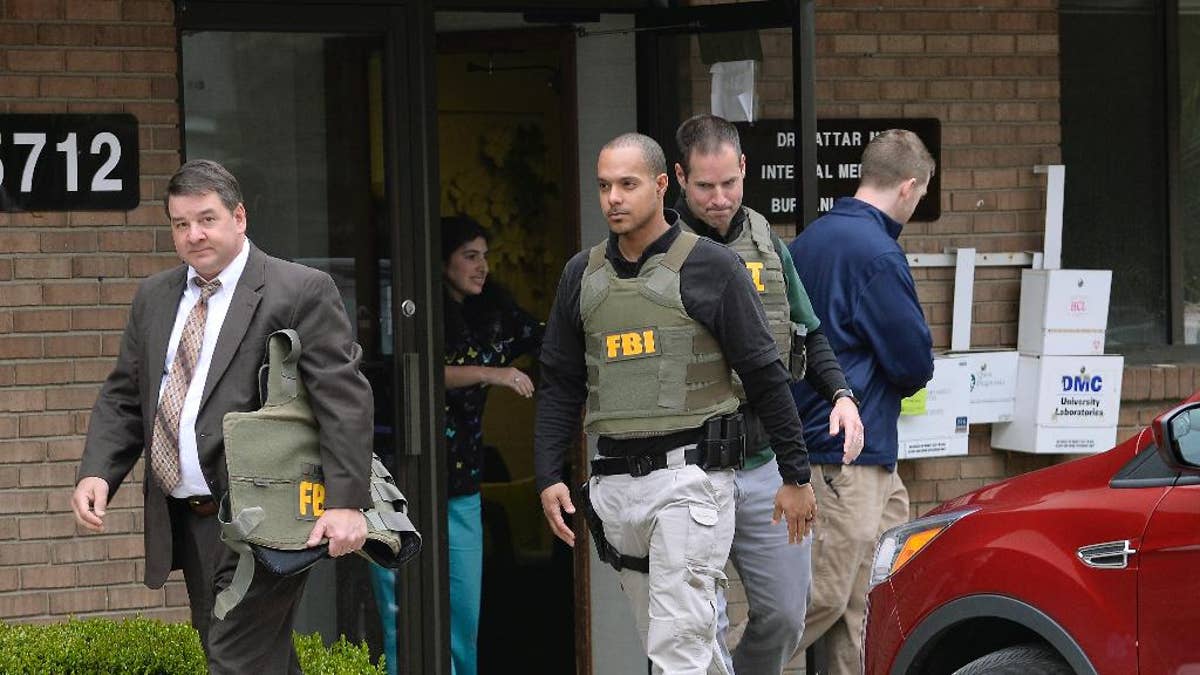 FBI agents leave the office of Dr. Fakhruddin Attar at the Burhani Clinic in Livonia, Mich. Friday, April 21, 2017, after completing a search for documents. The investigation is connected to the case of Dr. Jumana Nagarwala, of Northville, charged with performing genital mutilation on two young girls from Minnesota. (Clarence Tabb Jr. /Detroit News via AP)