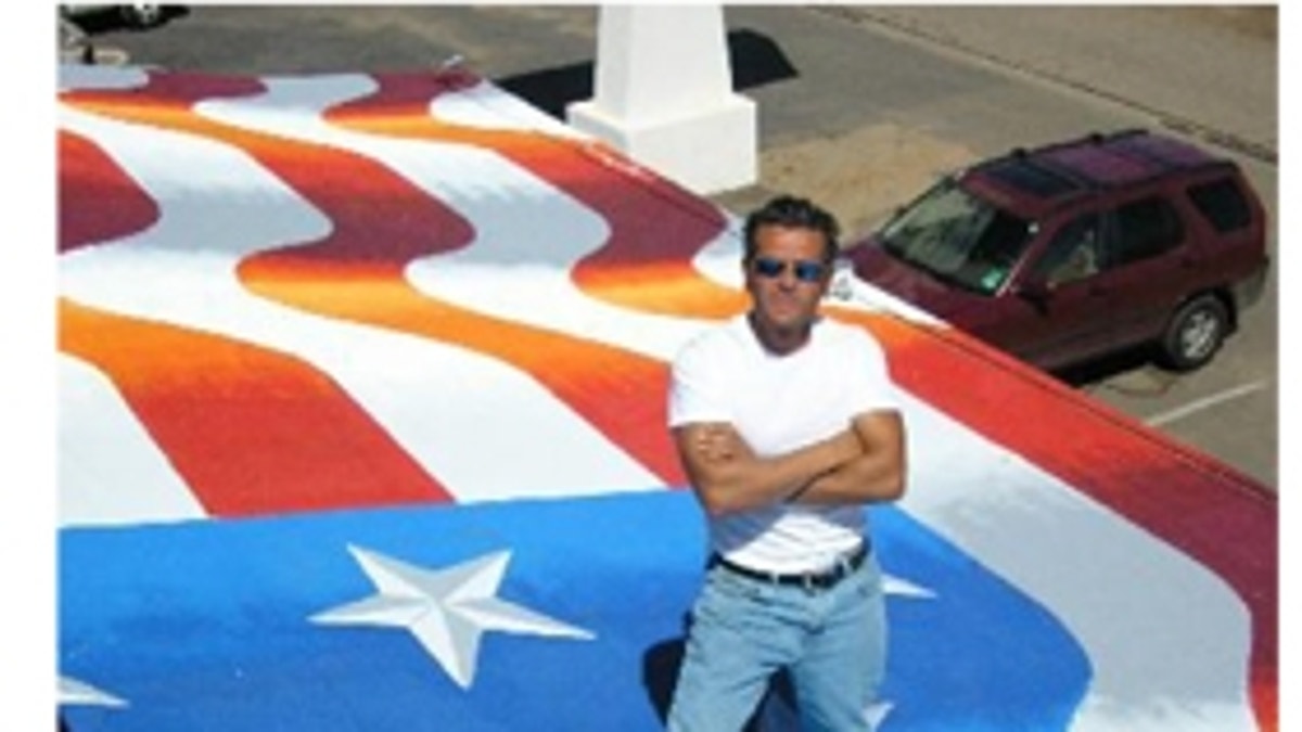 Artist Scott LoBaido showcasing his flag painting on a rooftop in Pioria, Ariz.