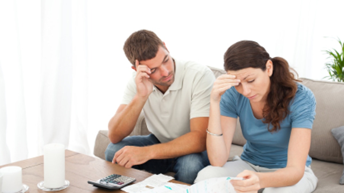 517397ea-Worried couple doing their accounts in the living room