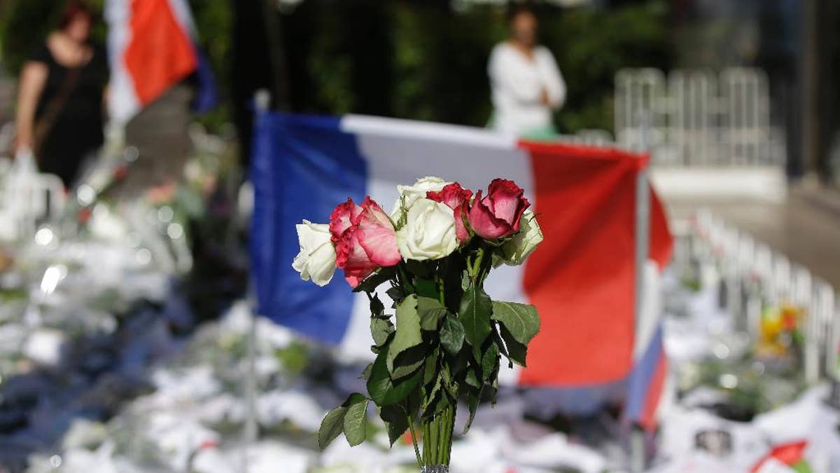 Floral and papers tributes are laid with a French flag near the scene of a truck attack in Nice, southern France, Saturday, July 16, 2016. Nice's seaside boulevard reopens to traffic Saturday following a dramatic truck attack which killed more than 80 people and wounded more than 200 others at a fireworks display. (AP Photo/Luca Bruno)