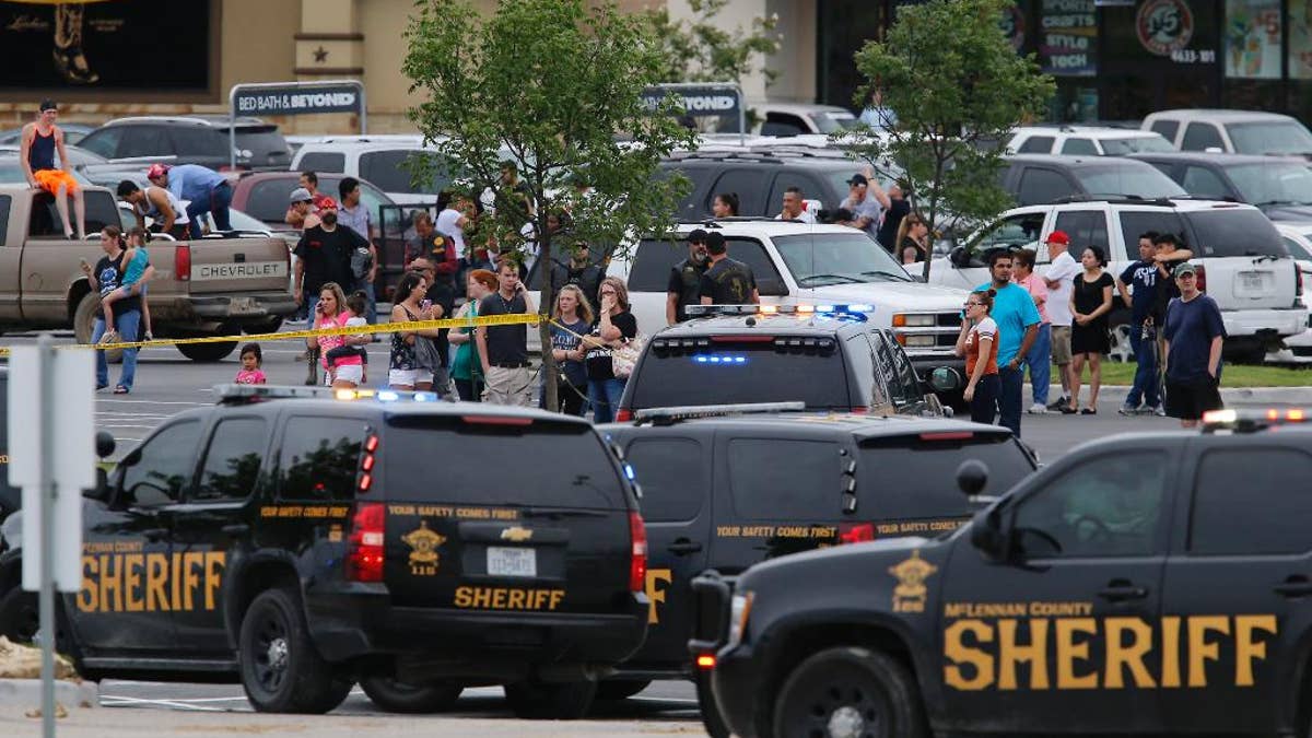 People at the Central Texas MarketPlace watch a crime scene near the parking lot of a Twin Peaks restaurant Sunday, May 17, 2015, in Waco, Texas. Waco Police Sgt. W. Patrick Swanton told KWTX-TV there were 