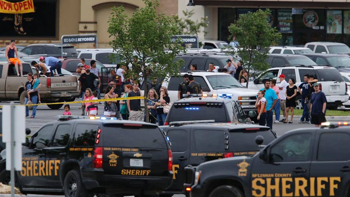 People at the Central Texas MarketPlace watch a crime scene near the parking lot of a Twin Peaks restaurant Sunday, May 17, 2015, in Waco, Texas. Waco Police Sgt. W. Patrick Swanton told KWTX-TV there were