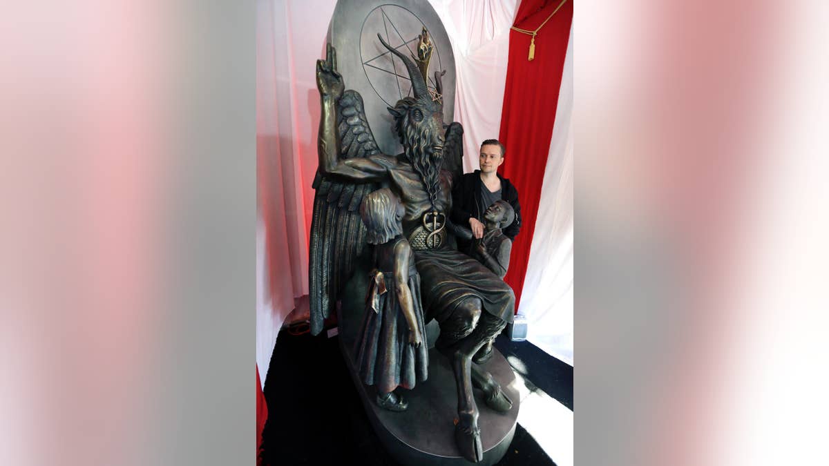 Lucien Greaves stands next to a 9-foot statue of the goat-headed idol Baphomet at the recently opened international headquarters of the Satanic Temple in Salem, Mass. The Satanic Temple is waging religious battles along a variety of fronts nationwide, and its co-founder says it's just getting started. Greaves says the temple hopes to ensure Satanists "have a place in the world" and that "evangelical theocrats" don't monopolize the religious freedom debate. (AP Photo/Elise Amendola)