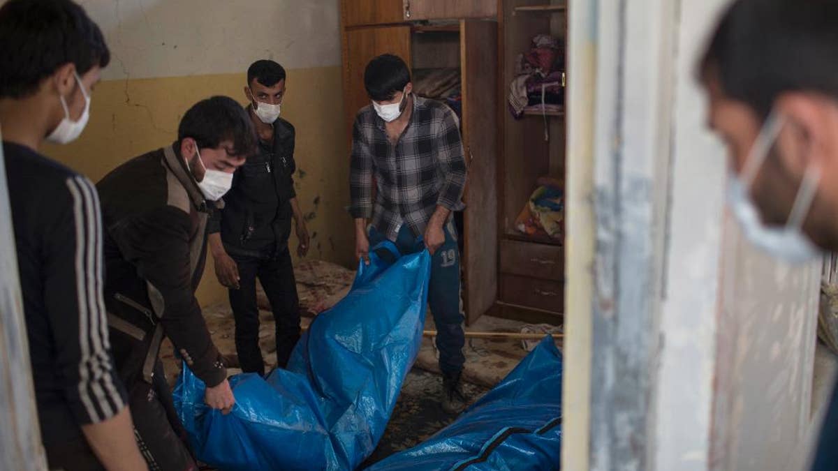 Residents carry the body of a person killed during fights between Iraq security forces and Islamic State on the western side of Mosul, Iraq, Friday, March 24, 2017.