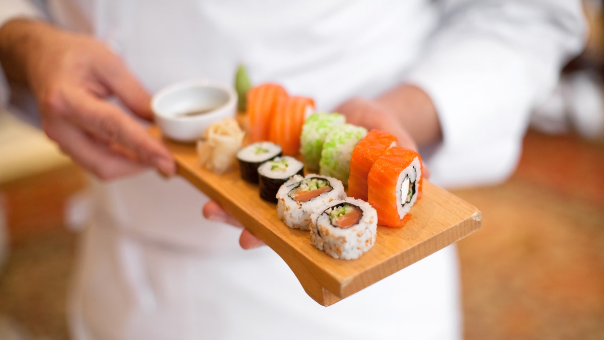 sushi chef holding sushi plate.