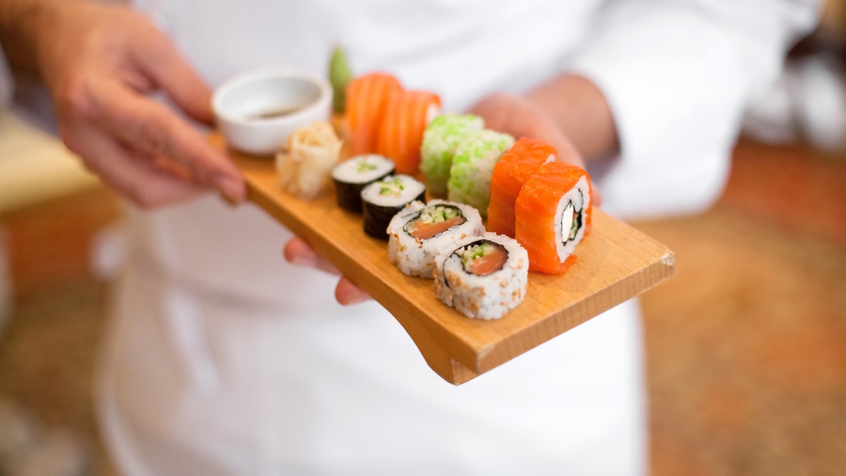 sushi chef holding sushi plate.