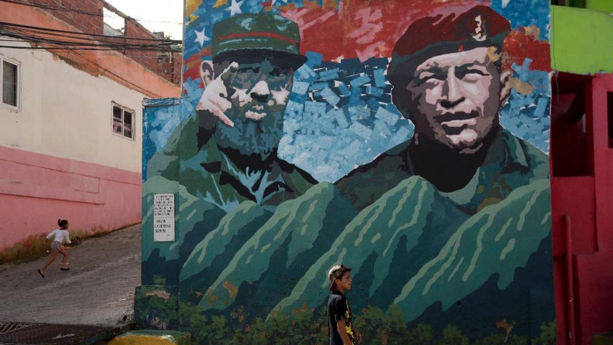 Boys play near a graffiti of Fidel Castro, left, and late President of Venezuela Hugo Chavez at "23 de Enero" neighborhood in Caracas, Venezuela, Saturday, Nov. 26, 2016. Castro, who led a rebel army to improbable victory, embraced Soviet-style communism and defied the power of 10 U.S. presidents during his half century rule of Cuba, died at age 90. (AP Photo/Fernando Llano)