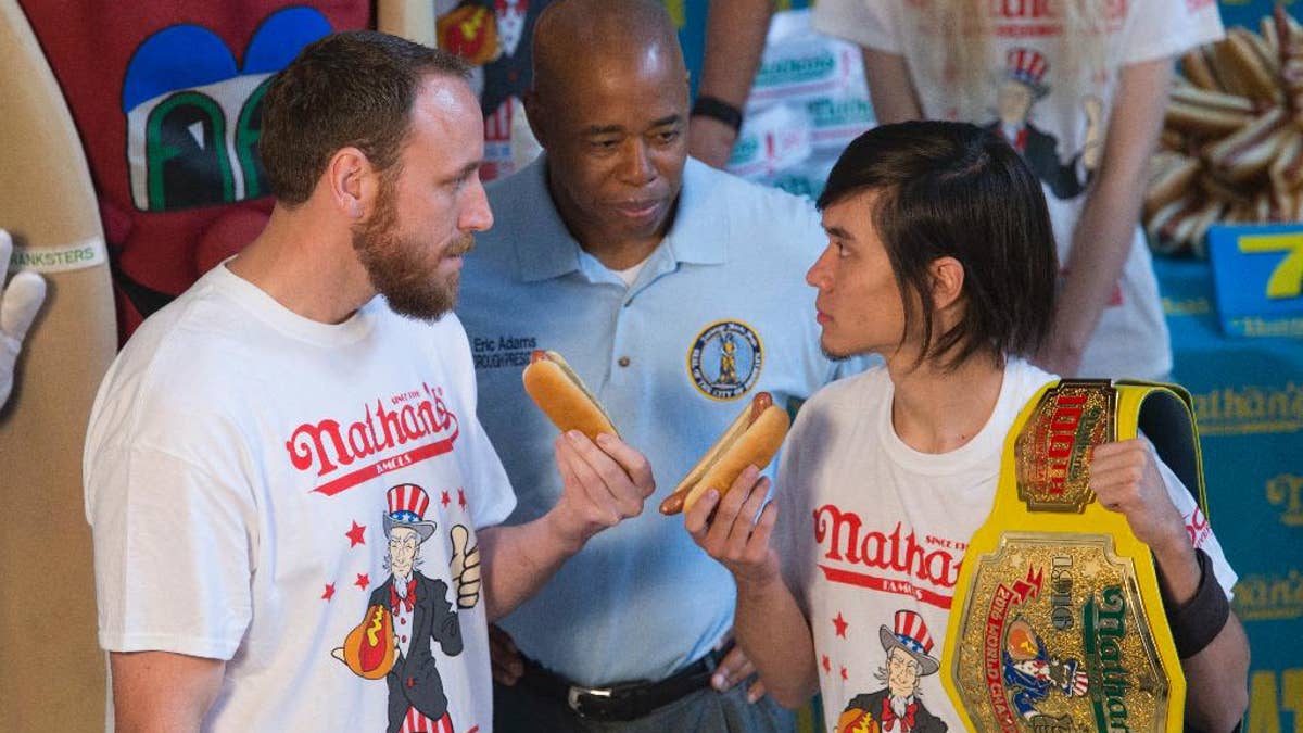 Matt Stonie, right, reigning hot dog-eating champion, stares down eight-time champion Joey Chestnut during the official weigh in for Nathans Famous hot dog eating contest, Friday, July 1, 2016, in New York. Brooklyn borough President Eric Adams stand between the men. (AP Photo/Mary Altaffer)
