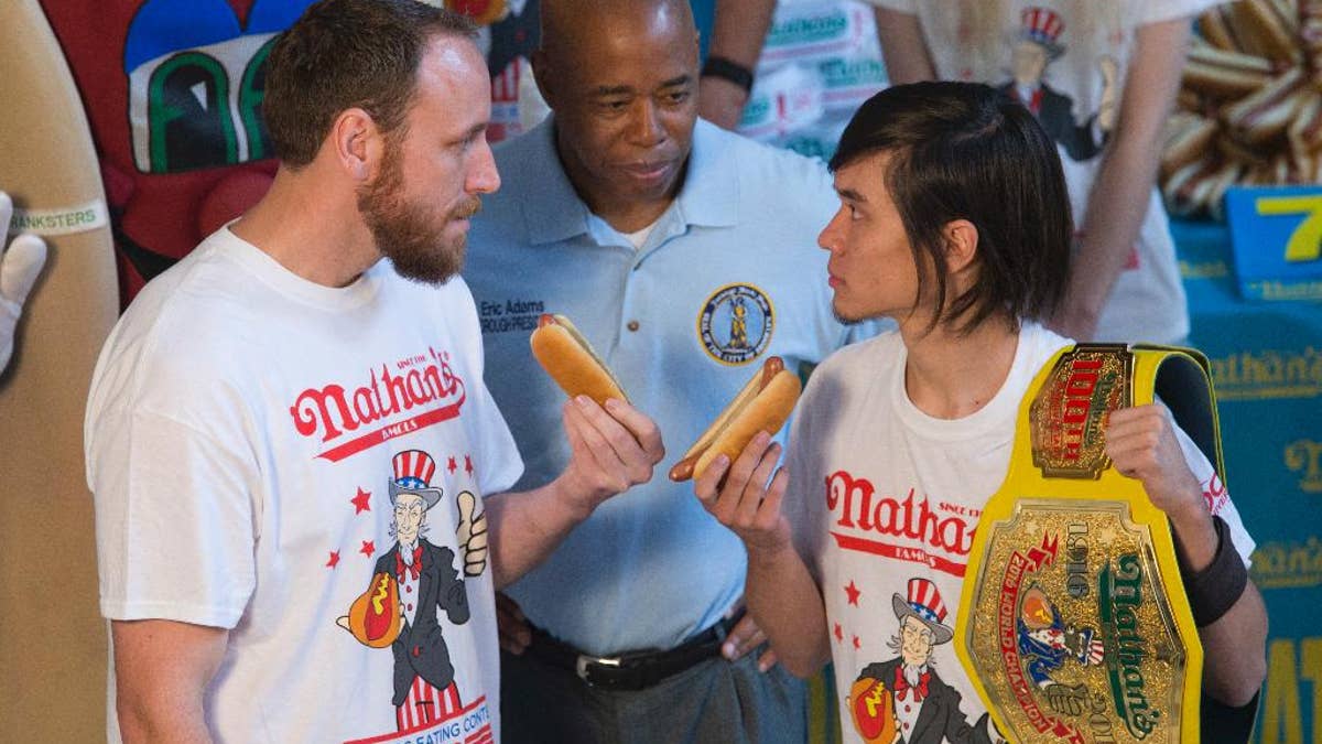 Matt Stonie, right, reigning hot dog-eating champion, stares down eight-time champion Joey Chestnut during the official weigh in for Nathans Famous hot dog eating contest, Friday, July 1, 2016, in New York. Brooklyn borough President Eric Adams stand between the men. (AP Photo/Mary Altaffer)