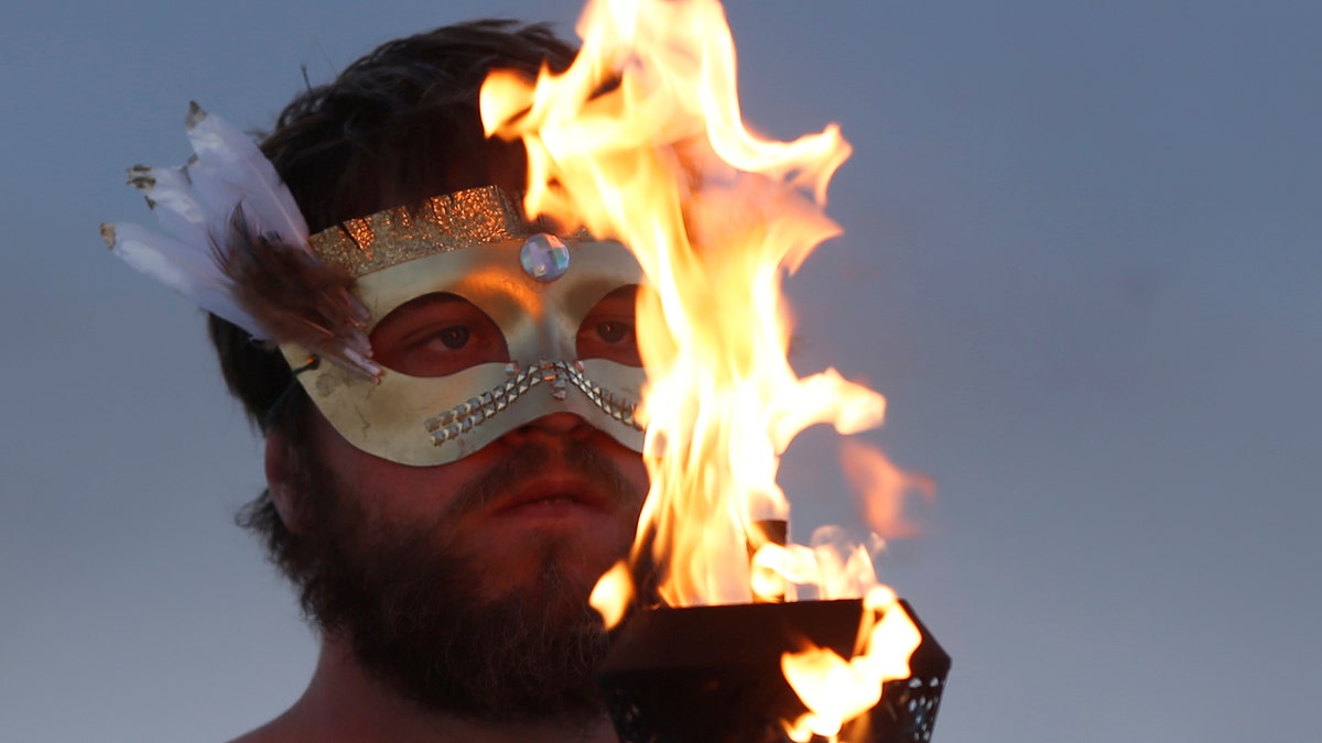 A participant takes part in a fire ceremony as approximately 70,000 people from all over the world gathered for the annual Burning Man arts and music festival in the Black Rock Desert of Nevada, U.S. August 28, 2017. REUTERS/Jim Urquhart FOR USE WITH BURNING MAN RELATED REPORTING ONLY. FOR EDITORIAL USE ONLY. NOT FOR SALE FOR MARKETING OR ADVERTISING CAMPAIGNS. NO THIRD PARTY SALES. NOT FOR USE BY REUTERS THIRD PARTY DISTRIBUTORS. - RTX3DRRE
