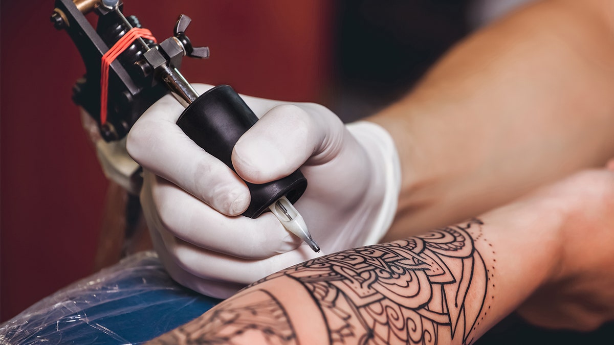 female tattooist tattooing upper arm of female customer - a Royalty Free  Stock Photo from Photocase