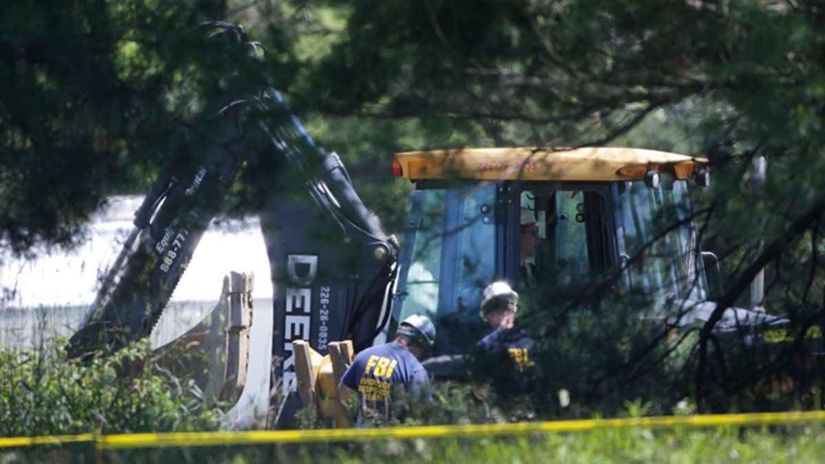 Members of an FBI evidence response team look over an area being cleared in Oakland Township, Mich., Tuesday, June 18, 2013 where officials continue the search for the remains of Teamsters union president Jimmy Hoffa, who disappeared from a Detroit-area restaurant in 1975. (AP Photo/Carlos Osorio)