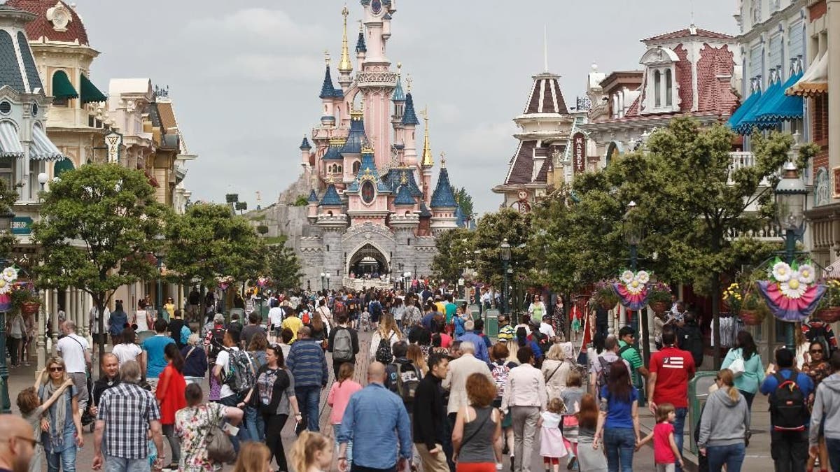FILE - In this May 12, 2015, file photo, visitors walk near Sleeping Beauty's Castle at Disneyland Paris, in Marne la Vallee, east of Paris. The Euro Disney group is going on trial in France, Wednesday May 25, 2016, for publishing an allegedly discriminatory job ad requesting that candidates have 