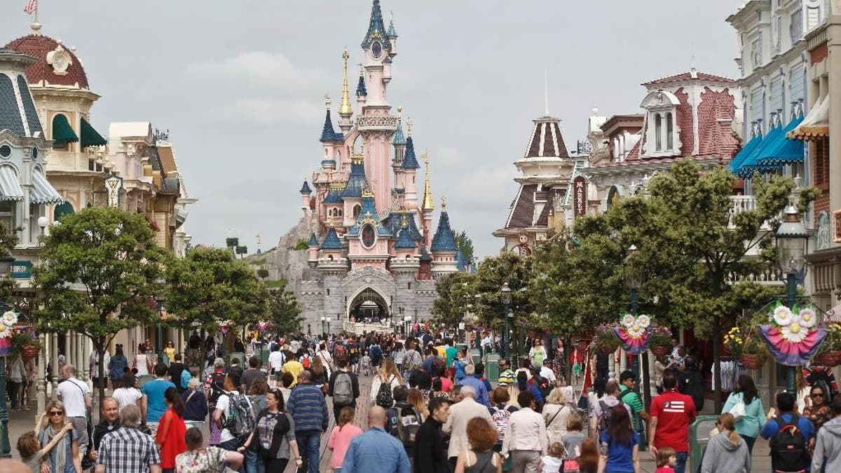 FILE - In this May 12, 2015, file photo, visitors walk near Sleeping Beauty's Castle at Disneyland Paris, in Marne la Vallee, east of Paris. The Euro Disney group is going on trial in France, Wednesday May 25, 2016, for publishing an allegedly discriminatory job ad requesting that candidates have 