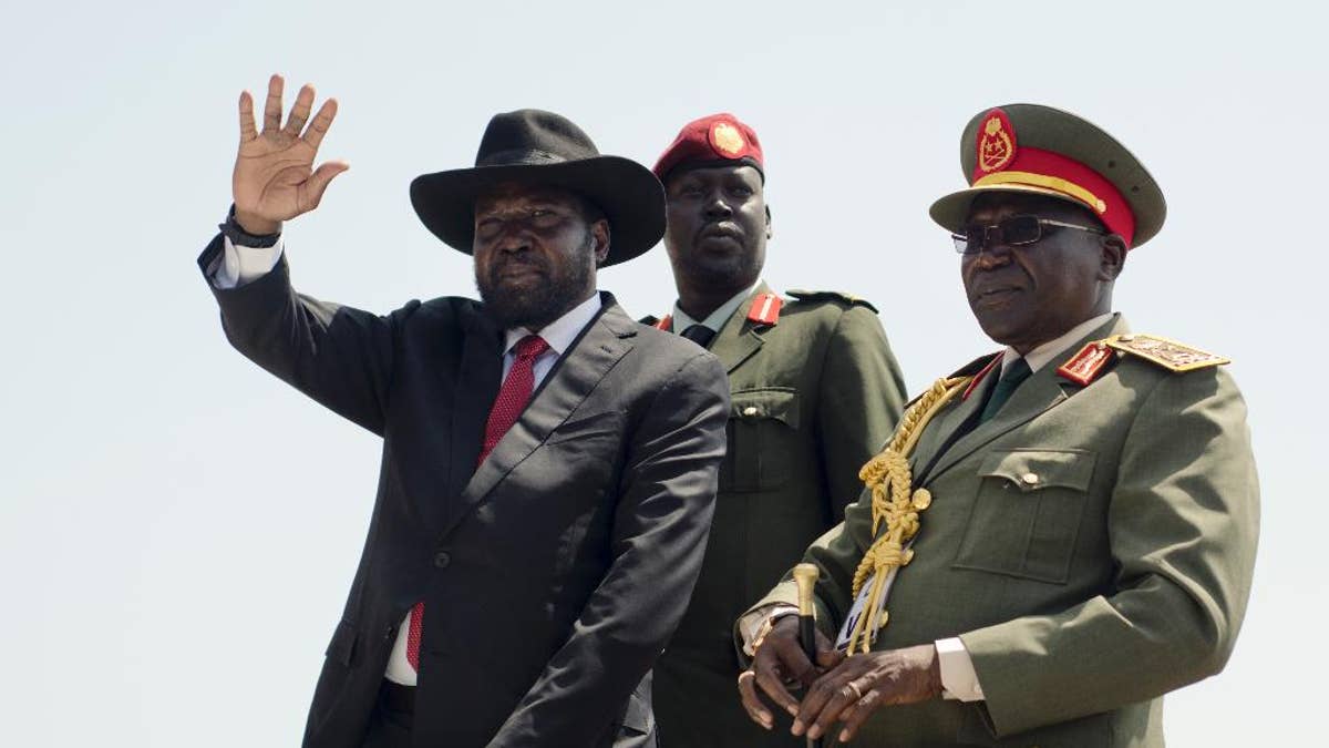 FILE - In this Thursday, July 9, 2015 file photo, South Sudan's President Salva Kiir, left, accompanied by army chief of staff Paul Malong, right, waves during an independence day ceremony in the capital Juba, South Sudan.  South Sudan's army chief of staff Paul Malong, who had been proposed for U.N. sanctions and accused of directing last year's fighting in the capital that left hundreds dead, has been removed from his post, a presidential spokesman said Tuesday, May 9, 2017. (AP Photo/Jason Patinkin, File)