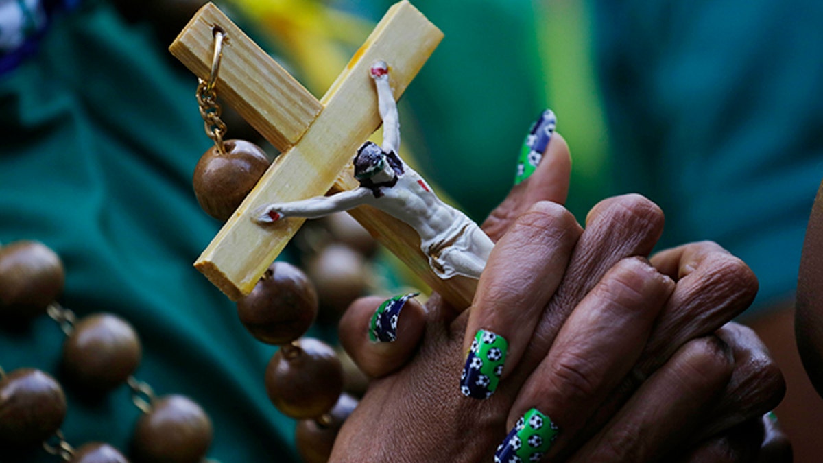 A Brazil soccer fan with soccer balls painted on her fingernails holds a crucifix as she watches the World Cup quarterfinal match between Brazil and Colombia inside the FIFA Fan Fest area in Sao Paulo, Brazil, Friday, July 4, 2014. (AP Photo/Nelson Antoine)