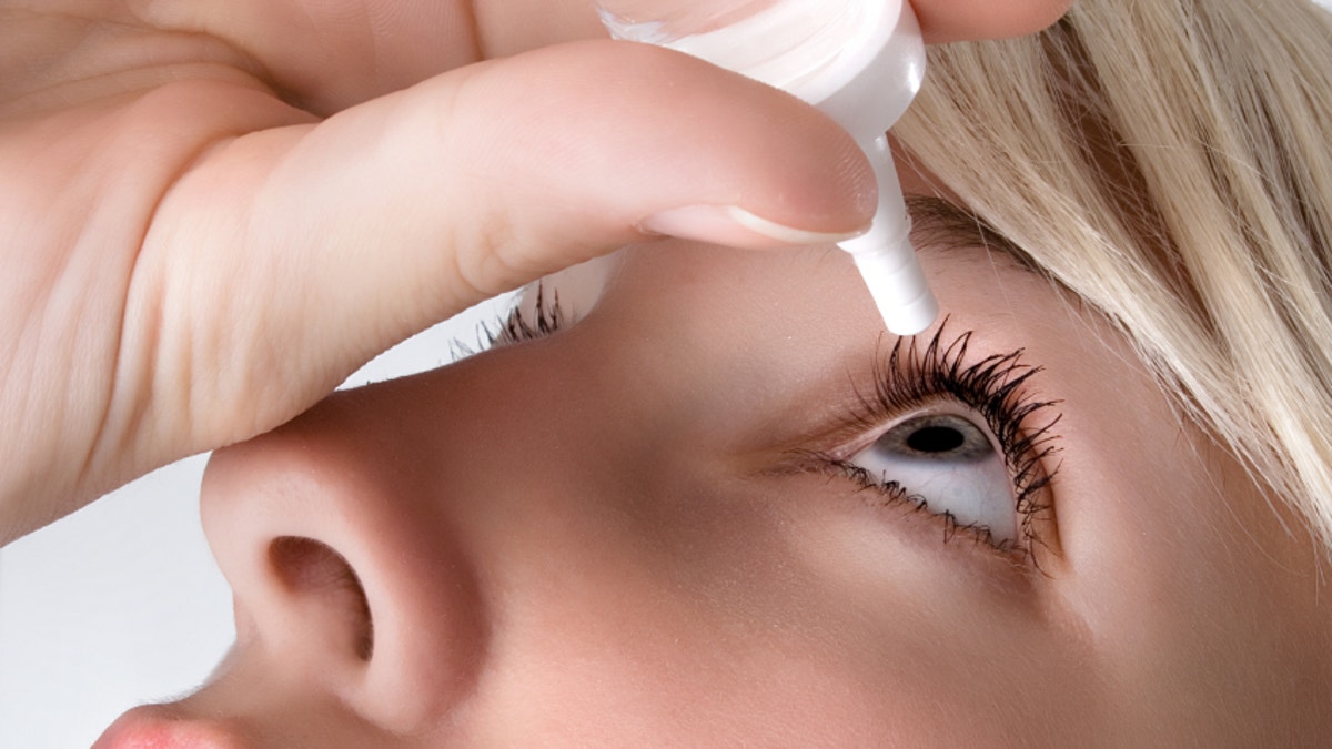 Woman applying eye drops, close up