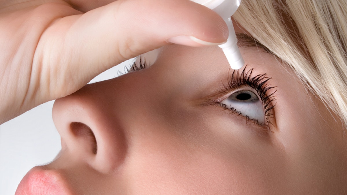 Woman applying eye drops, close up