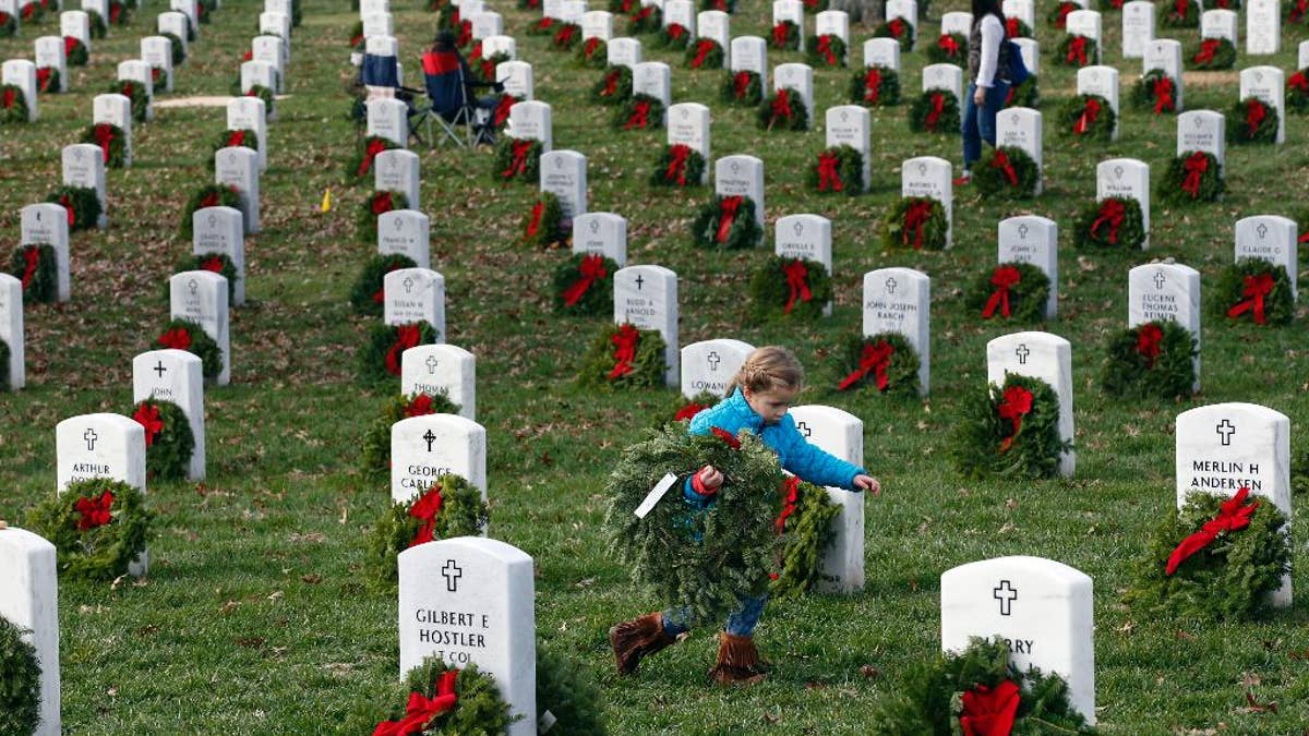 Lane Austin, 6, of Virginia Beach, Va., carries a wreath to grave during Wreaths Across America at Arlington National Cemetery, Saturday, Dec. 12, 2015 in Arlington, Va. Organizers estimated that volunteers placed 240,815 wreaths at Arlington.(AP Photo/Alex Brandon)