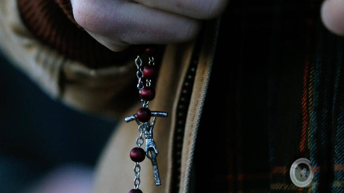 Reid Johnson prays with rosary beads