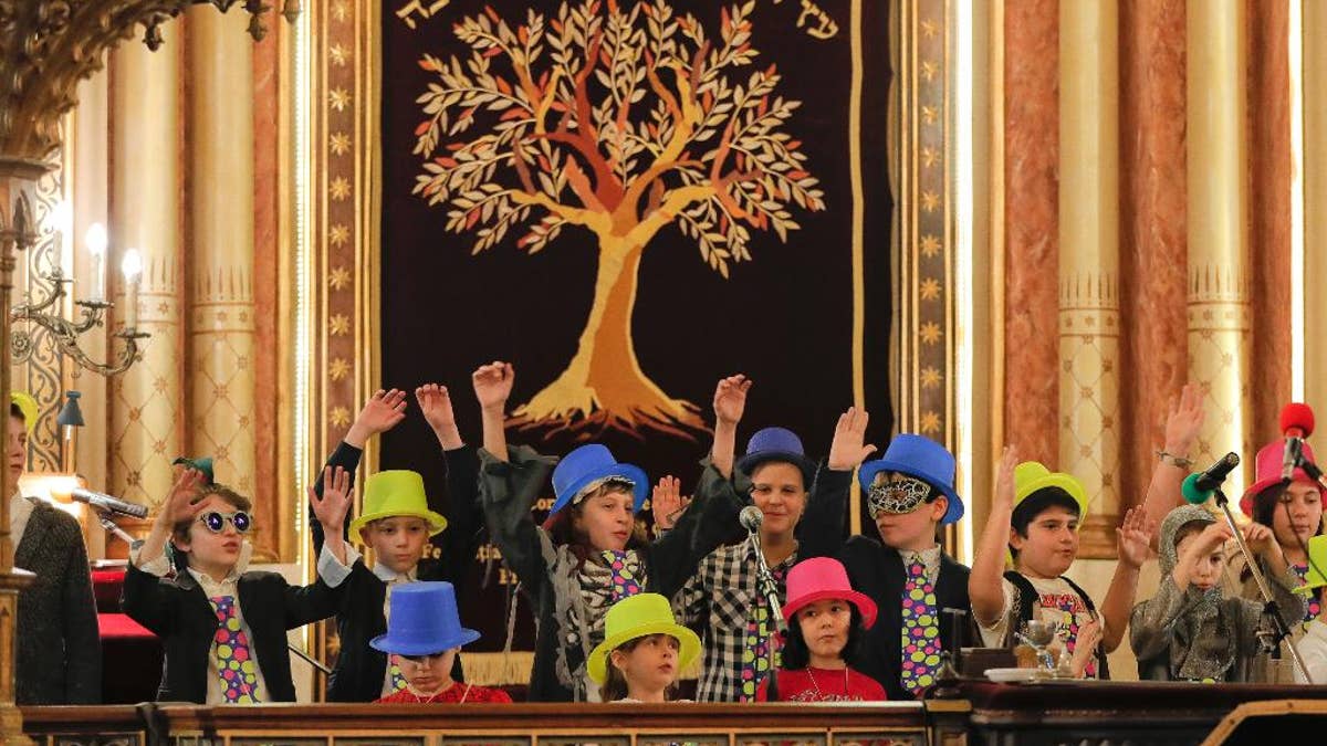 In this March 11, 2017 picture, children sing during Purim celebrations at the Coral Temple synagogue in Bucharest, Romania. Children put on fancy costume dress joining dozens of believers from Romania's Jewish community who attended a Purim service to celebrate the Jews' salvation from genocide in ancient Persia, as recounted in the Book of Esther.(AP Photo/Vadim Ghirda)