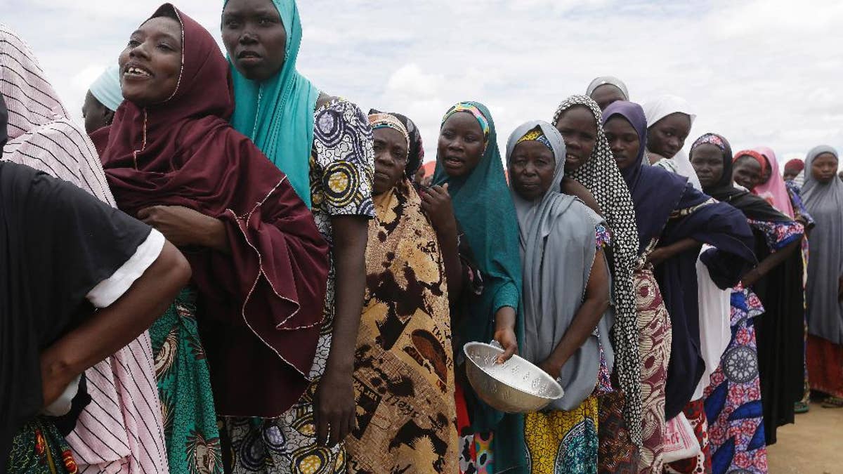FILE-In this file photo taken Saturday, Aug. 27, 2016, women displaced by Islamist extremists wait for food to be handed out to them at the Bakassi camp in Maiduguri, Nigeria. Many say the dangerous journey is preferable to the hunger, humiliation and inhumane conditions in refugee camps where more than 1 million Nigerians, displaced by Boko Haram, are waiting to go home. Many are in Maiduguri, the biggest city in the northeast, the birthplace of Boko Haram, which has killed more than 20,000 and forced 2.6 million from their homes. (AP Photo/Sunday Alamba,File)
