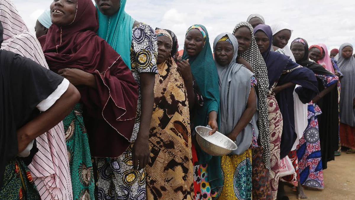 FILE-In this file photo taken Saturday, Aug. 27, 2016, women displaced by Islamist extremists wait for food to be handed out to them at the Bakassi camp in Maiduguri, Nigeria. Many say the dangerous journey is preferable to the hunger, humiliation and inhumane conditions in refugee camps where more than 1 million Nigerians, displaced by Boko Haram, are waiting to go home. Many are in Maiduguri, the biggest city in the northeast, the birthplace of Boko Haram, which has killed more than 20,000 and forced 2.6 million from their homes. (AP Photo/Sunday Alamba,File)