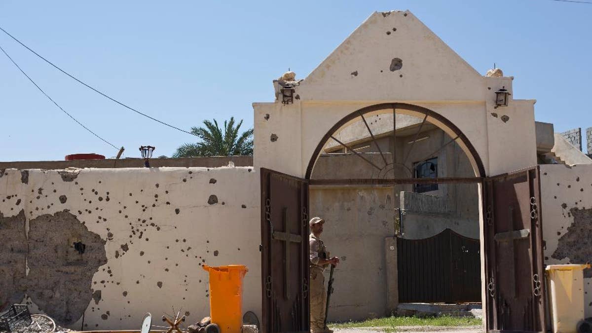 A Christian militiaman stands guard during Easter Mass in Qaraqosh, Iraq, Sunday, April 16 2017. The town has been gutted by Islamic State militants. Now under government control, residents have not returned. (AP Photo/Maya Alleruzzo)