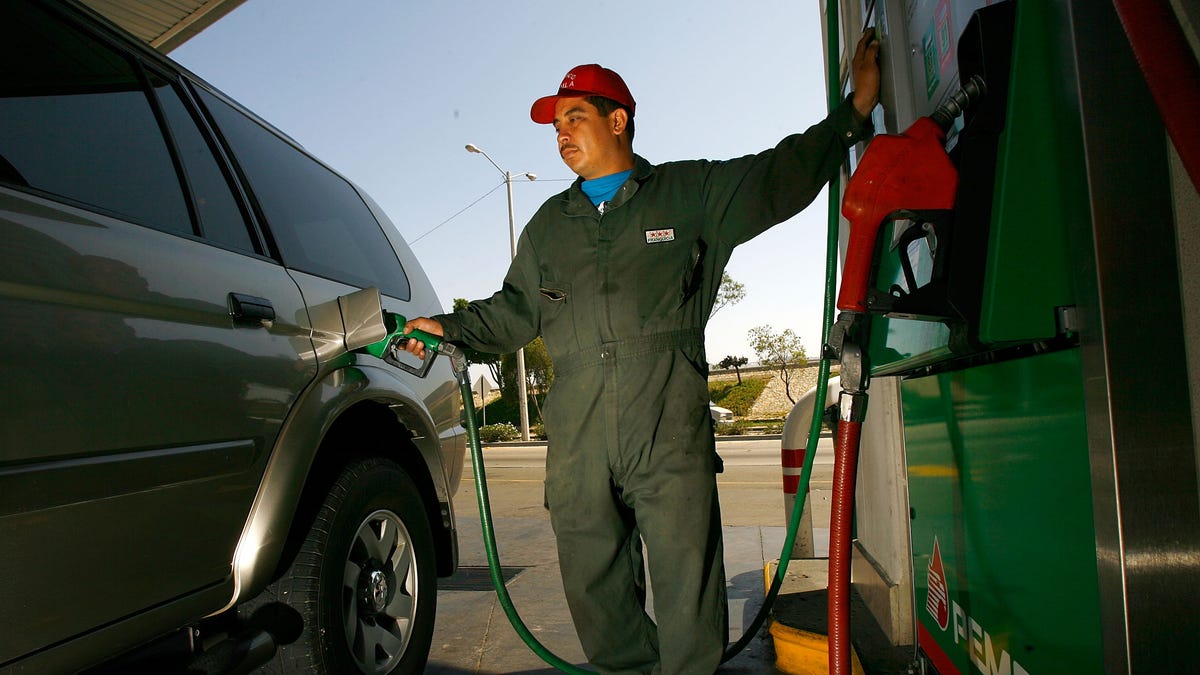 TIJUANA, MEXICO - JUNE 27:  A Pemex gas station attendant fills a car registered with a California license plate on June 27, 2008 in Tijuana, Mexico. With the cost of gasoline in California around $4.60 per gallon, many drivers are buying their fuel in Mexico for about $3.20. There is a price to pay for cheaper gas though. Mexican gas is formulated with more sulfur than California gas and that can damage the emission control equipment on US cars, causing them to fail emissions tests and leading to expensive repairs. In addition, unless a driver has other business in Mexico, part of their fuel savings will be burned up idling in a line that can easily last for hours to get back into the US.  (Photo by David McNew/Getty Images)
