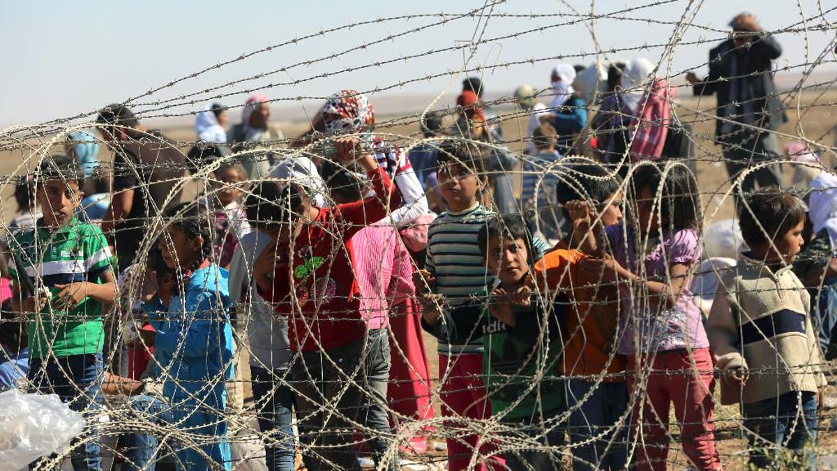 Mehrere hundert syrische Flüchtlinge warten am Sonntag, 21. September 2014, an der Grenze in Suruc, Türkei, auf die Einreise in die Türkei. Die Türkei öffnete am Samstag ihre Grenze, um bis zu 60.000 Menschen aufzunehmen, die sich an der türkisch-syrischen Grenze auf der Flucht vor militanten Islamisten versammelt hatten ' Vormarsch auf Kobani. (AP Photo/Burhan Ozbilici)