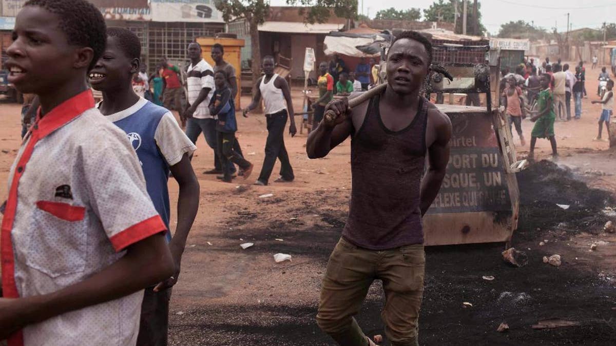 People protesting against the recent coup in the street as they walk among the  burnt remains of  tires  in the city of Ouagadougou,  Burkina Faso, Thursday, Sept. 17, 2015.  While gunfire rang out in the streets, Burkina Faso’s military took to the airwaves Thursday to declare it now controls the West African country, confirming that a coup had taken place just weeks before elections. (AP Photo/Theo Renaut)