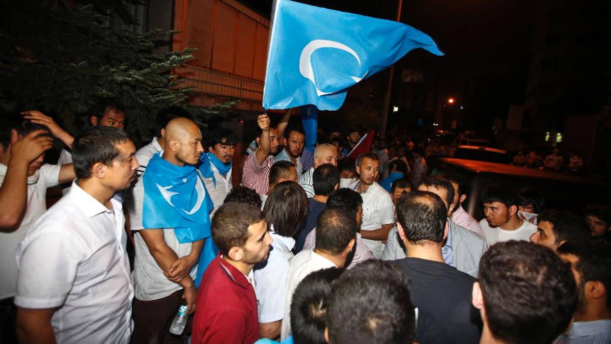 Uighurs living in Turkey and Turkish supporters, some carrying flags of East Turkestan, the term separatist Uighurs and Turks use to refer to the Uighurs homeland in China's Xinjiang region, gather outside the Thai consulate in Istanbul, early Thursday, July 9, 2015. A group of protesters stormed the consulate overnight, smashing windows and breaking in to the offices, where they destroyed pictures and furniture and hurled files out into the yard, to denounce Thailand’s decision to deport 109 ethnic Uighur migrants back to China. Turkey has cultural ties to the minority Muslim Uighurs and pro-Uighur groups fear the 109 face persecution by the Chinese government. (AP Photo)