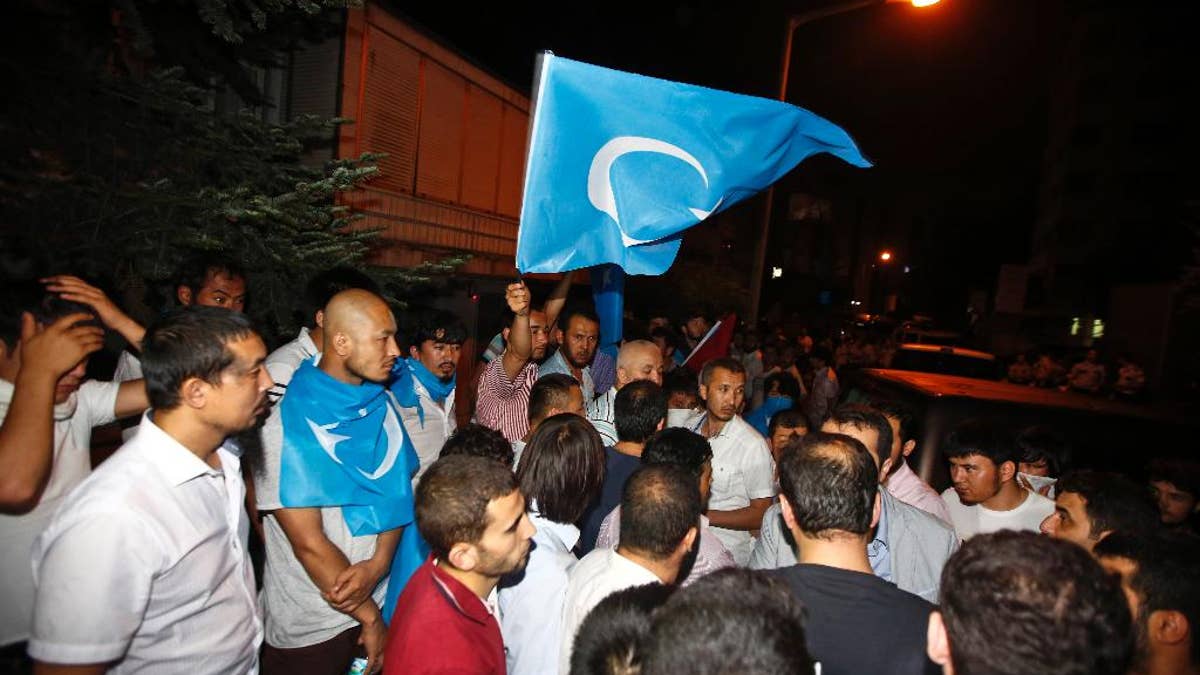 Uighurs living in Turkey and Turkish supporters, some carrying flags of East Turkestan, the term separatist Uighurs and Turks use to refer to the Uighurs homeland in China's Xinjiang region, gather outside the Thai consulate in Istanbul, early Thursday, July 9, 2015. A group of protesters stormed the consulate overnight, smashing windows and breaking in to the offices, where they destroyed pictures and furniture and hurled files out into the yard, to denounce Thailand’s decision to deport 109 ethnic Uighur migrants back to China. Turkey has cultural ties to the minority Muslim Uighurs and pro-Uighur groups fear the 109 face persecution by the Chinese government. (AP Photo)